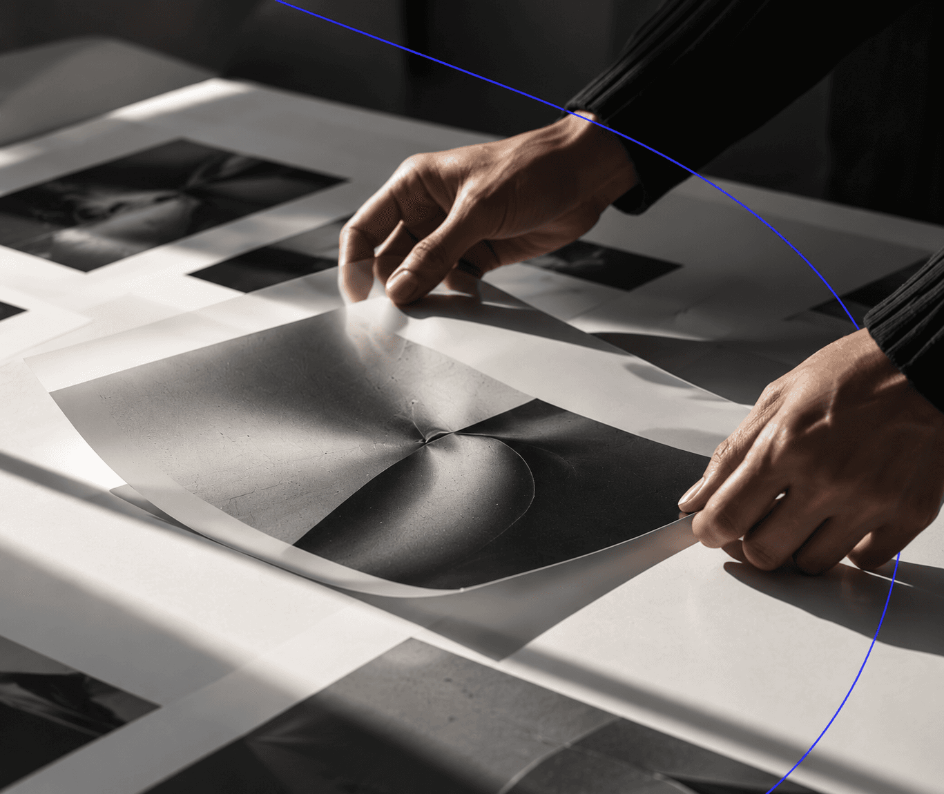 Hands laying out black and white prints on a studio table